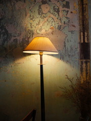 Vintage lamp shines on the background of a ruined wall. Vertical photo