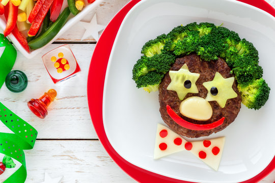 Fun food for kids - cute smiling face of a funny clown made of meat burger, broccoli and cheese. Healthy eating for children
