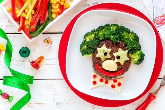 Fun food for kids - cute smiling face of a funny clown made of meat burger, broccoli and cheese. Healthy eating for children