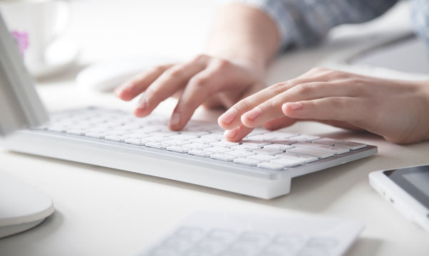 Hands typing on computer keyboard in office desk.