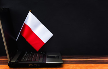 flag of Poland , computer, laptop on table and dark background