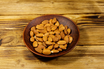 Almonds in ceramic plate on a rustic wooden table