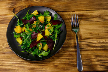 Tasty salad of fresh arugula, beetroot and oranges on wooden table. Top view. Healthy food or vegetarian concept
