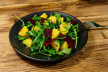 Tasty salad of fresh arugula, beetroot and oranges on wooden table. Healthy food or vegetarian concept