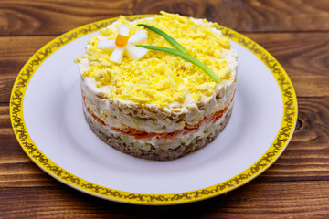 Traditional russian layered salad Mimosa with spring decoration Daffodil. Decoration is made of egg, green onion and carrot