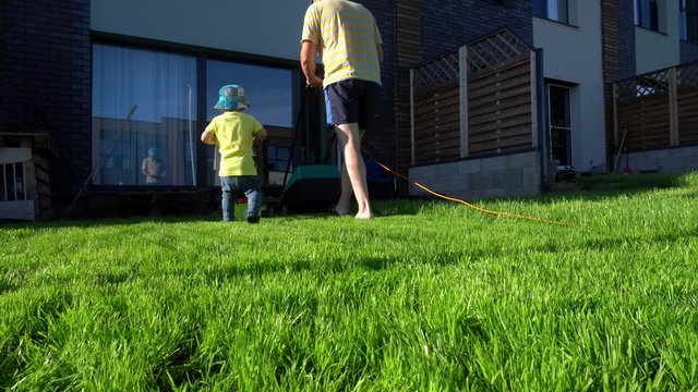 Family boys father and son cut mow lawn grass in private yard. Gimbal movement