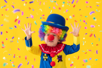 Fototapeta premium Funny kid clown playing against yellow background
