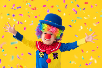 Fototapeta premium Funny kid clown playing against yellow background