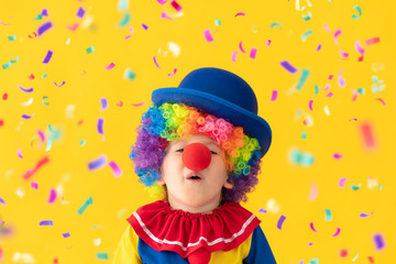 Fototapeta premium Funny kid clown playing against yellow background