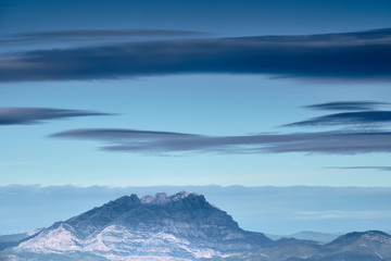 Fototapeta na wymiar Granite mountain with blue atmosphere and big clouds, Montserrat, Catalonia
