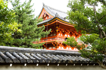 Photograph of the tower of a red Japanese temple surrounded by trees