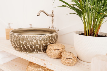 round dark unusual stone sink on a wooden countertop and reusable organic woven from straw bath accessories © Aleksandra
