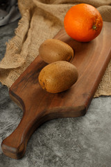 Orange and kiwies on a rustic wooden board. Top view.