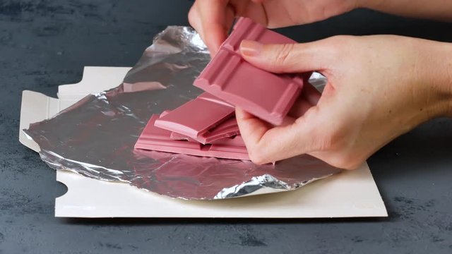 Breaking Ruby chocolate bar on pieces. New dimension of chocolate sweets.