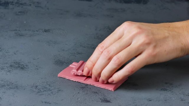 Chunks of broken ruby chocolate stacked on blackboard.