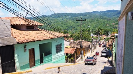 honduras copan street with cars and tuk tuk and a dog