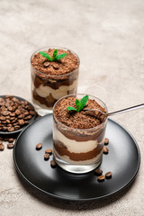Classic tiramisu dessert in a glass cup on concrete background