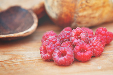 Raspberries on a wooden table near wooden utensils