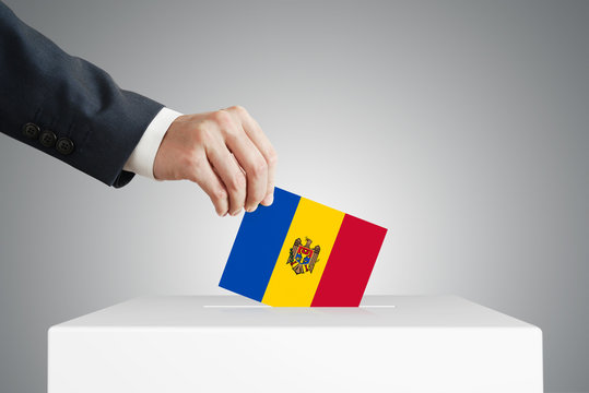 Man putting a voting ballot into a box with Moldovan flag.