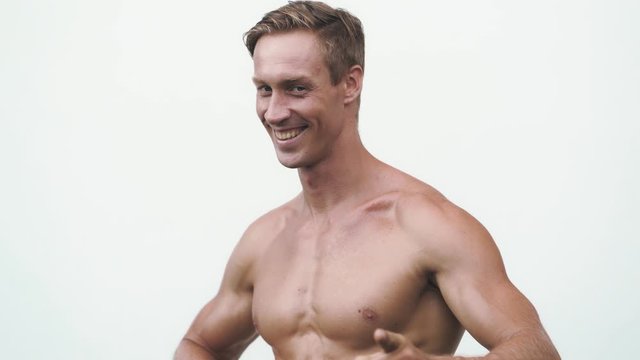 Shirtless man on white background, shows thoughtful emotion on his face then laughs