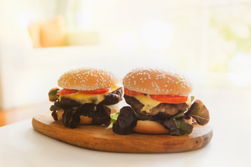 Close-up photo of home made Two large pieces of homemade hamburger pork, stacked with layers of delicious organic vegetables, placed on a wooden chopping board ready to eat.