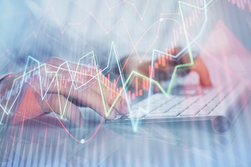 Double exposure of graph with man typing on computer in office on background. Concept of hard work.