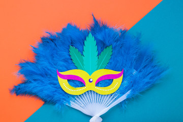 Flat lay of mask on feathers fan for carnival