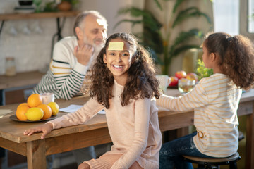 Fototapeta premium Two dark-skinned girls playing guess game with their granddad