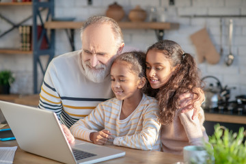 Grey-haired bearded man and his granddaughters having a video call