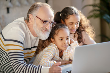 Grey-haired bearded man spending time with his granddaughters