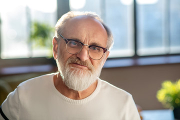 Close up picture of grey-haired bearded man in eyeglasses smiling nicely