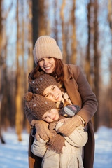 Fototapeta na wymiar Mother and daughters hugging in winter snow forest