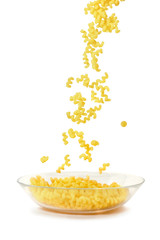 Macaroni falling into a glass plate on a white background