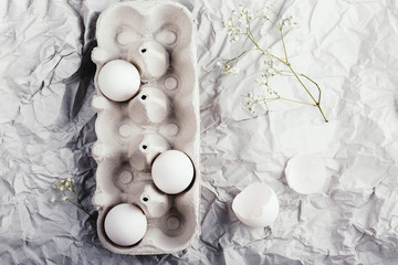Easter eggs in a carton box, top view, spring flowers and freshen up