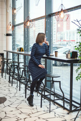 cute young woman in a cafe looks at her watch and waits for someone. vertical photo