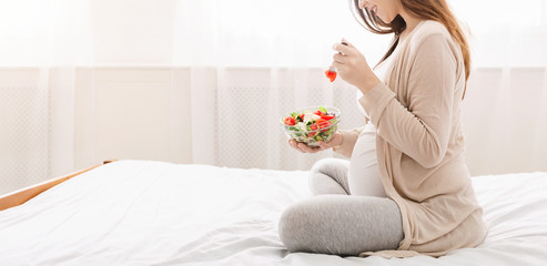 Obraz na płótnie Canvas Pregnant woman enjoying natural vegetable salad in bed