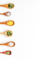 Colorful spa salt in spoons on white background top-down frame copy space