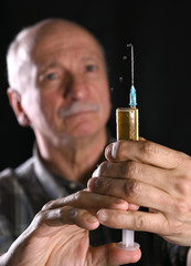 Senior man holding syringe over black background