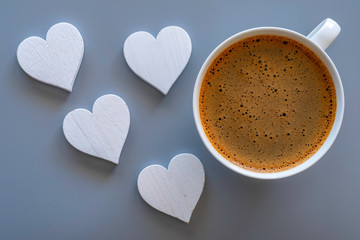 Top view of coffee cup and decorative white wooden hearts on grey background. Valentine day...