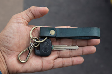 Black car keys in hand, along with brass rings and blue leather keys to prevent them from being...