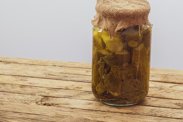 Jar of pickled vegetables on a wooden surface with a light background