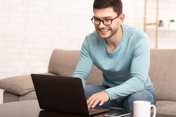 Smiling Freelancer Man Working On Laptop Sitting At Home