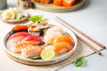 Ensemble de sushi et maki sur assiette avec sauce soja et baguettes sur fond blanc. Vue de dessus avec espace de copie