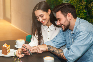 Boyfriend And Girlfriend Using Phone During Date In Cafe