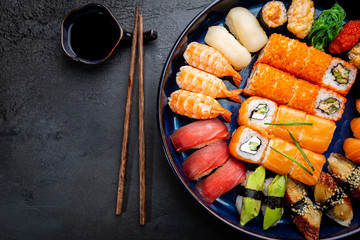 Set of sushi and maki with soy sauce over black background. Top view with copy space