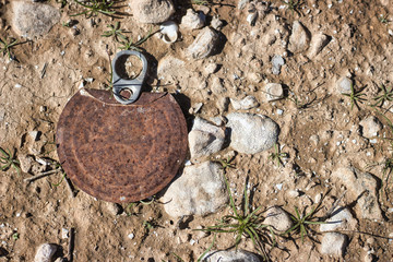 Part of a rusty tin can on soil and green grass background.