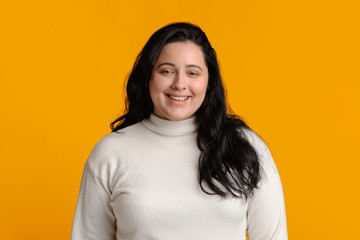 Portrait of happy millennial plump woman smiling at camera