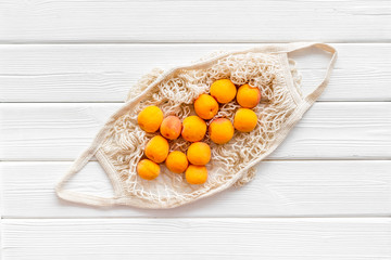 Eco-friendly package. Eco bag with fruits on white wooden background top-down