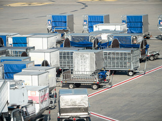 Image of lots of luggage and cargo delivery carts in airport ground service parking
