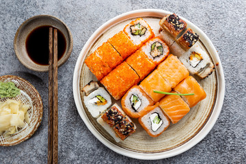 Set of sushi and maki with soy sauce over stone gray background. Top view with copy space